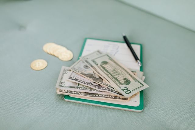 dollar bills and coins on a journal with a pen